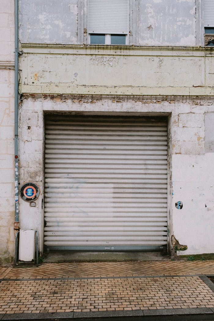 services-01 An old garage door with a weathered wall, showcasing urban decay and texture.