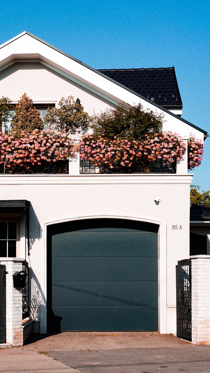 gallery-5 Stylish urban house in Cluj-Napoca featuring a garage and flowering balcony under a clear blue sky.