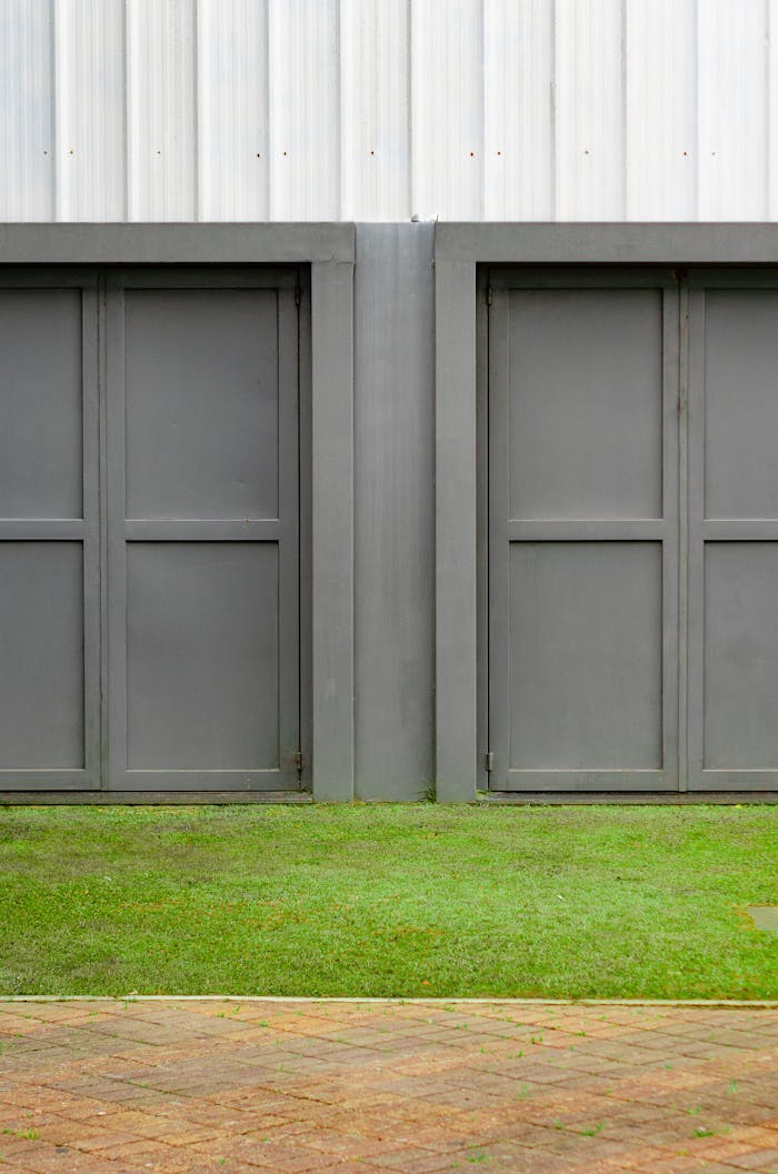 services-img Close-up of two modern gray garage doors with grass and pavement.