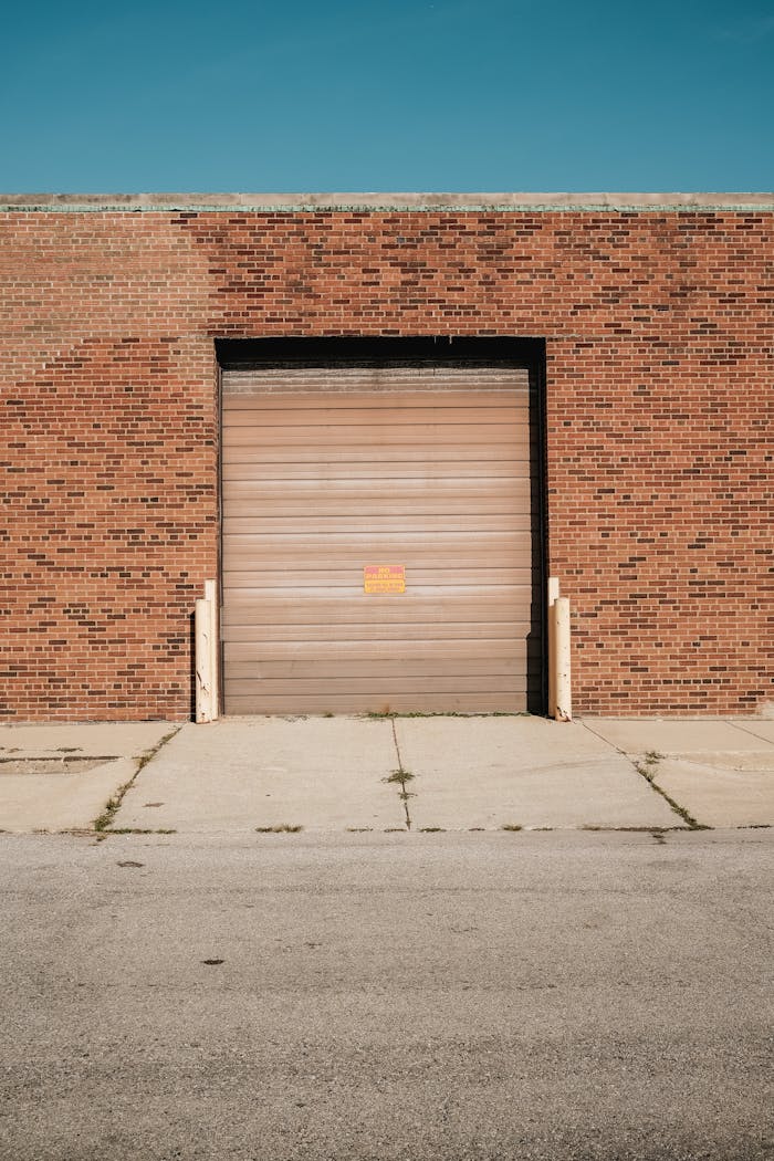 gallery-3 A brick warehouse with a closed roller door under a clear blue sky.