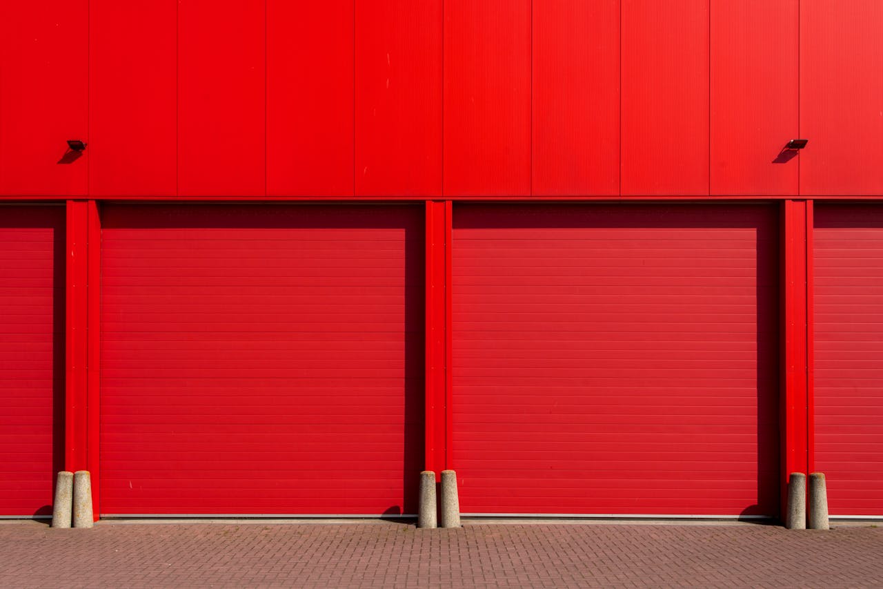 hero-img-02 Vivid red garage doors in a sleek industrial building, exuding modern architecture.