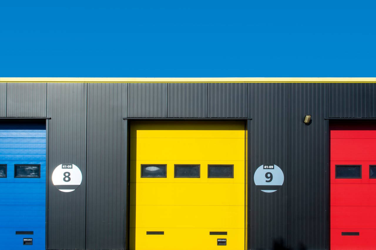 services-04 Brightly colored industrial garage doors with primary colors against a clear sky.