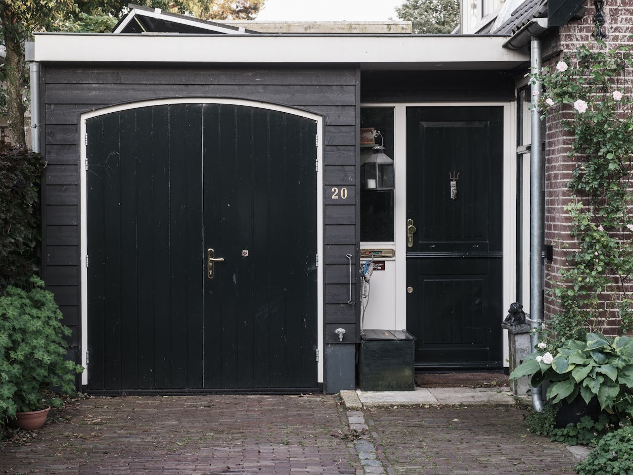 our-experience Exterior of a traditional Dutch house with black doors and a landscaped garden.