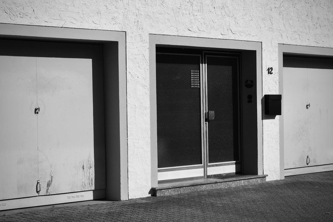 services-02 Monochrome photo of an urban building facade with garages and doors.