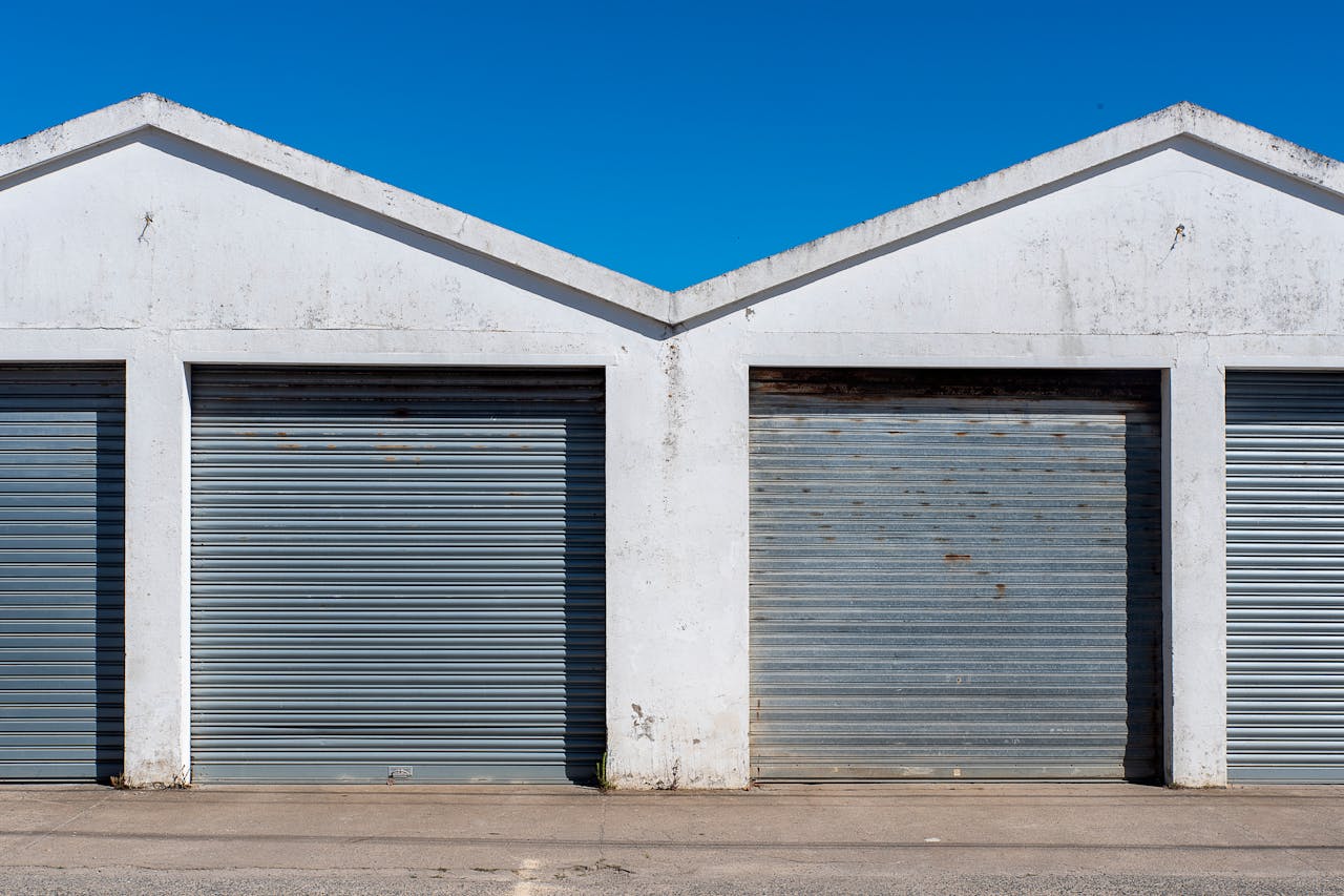 services-03 Image of industrial garage doors with corrugated metal under a clear blue sky, featuring a minimalist architectural style.