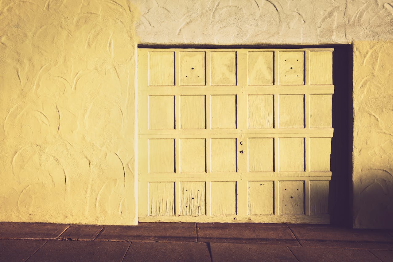 about-02 A vintage wooden garage door set against a textured wall in warm, muted tones.